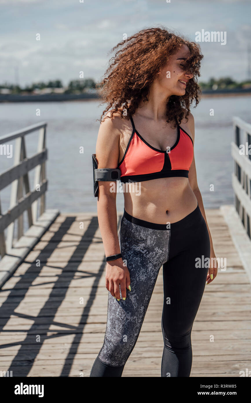 Lächelnd sportliche junge Frau, die am Flußufer Stockfoto