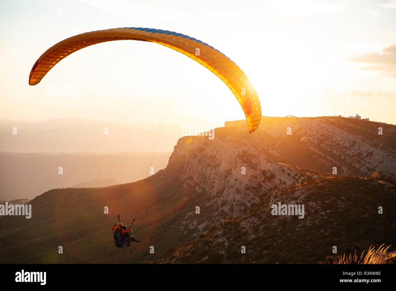 Spanien, Silhouette von Gleitschirm soaring hoch über die Berge bei Sonnenuntergang Stockfoto