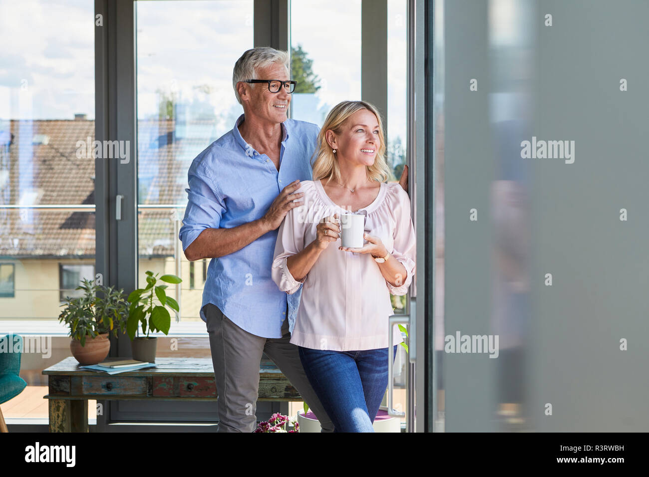 Lächelnd reifes Paar entspannt zu Hause Blick aus Fenster Stockfoto