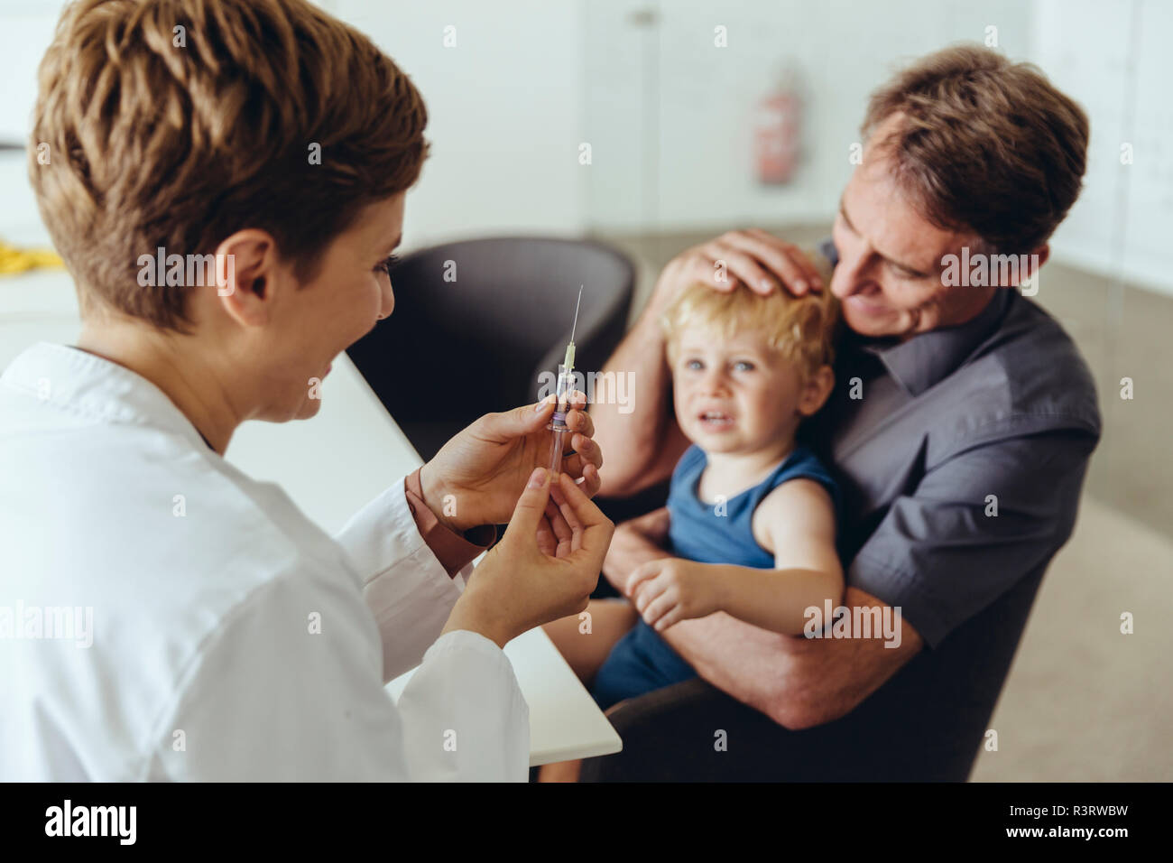 Vater, Sohn, während sie von pedeatrician geimpft werden Stockfoto