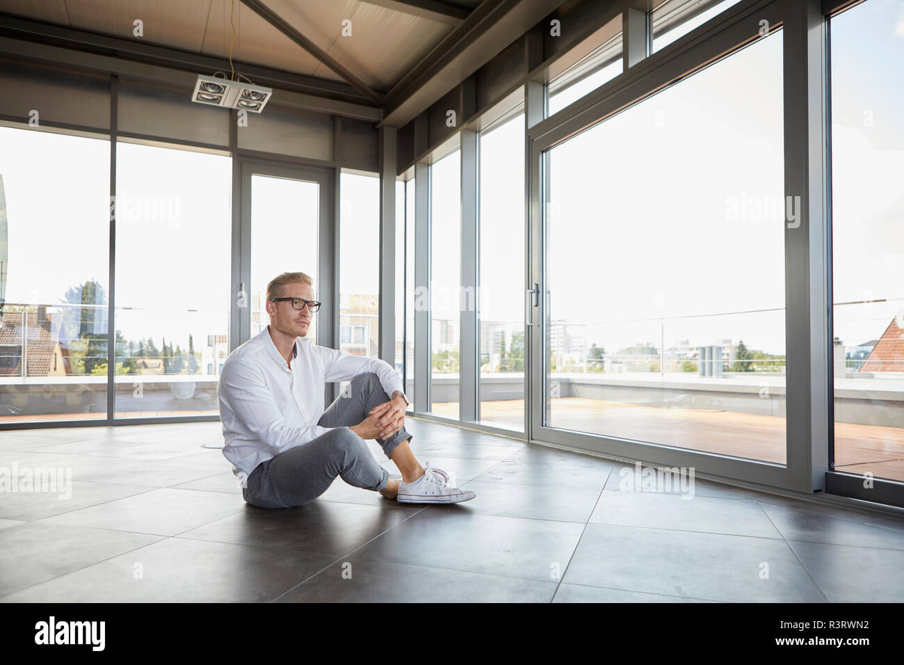 Geschäftsmann sitzt im leeren Raum aus Panorama Fenster Stockfoto