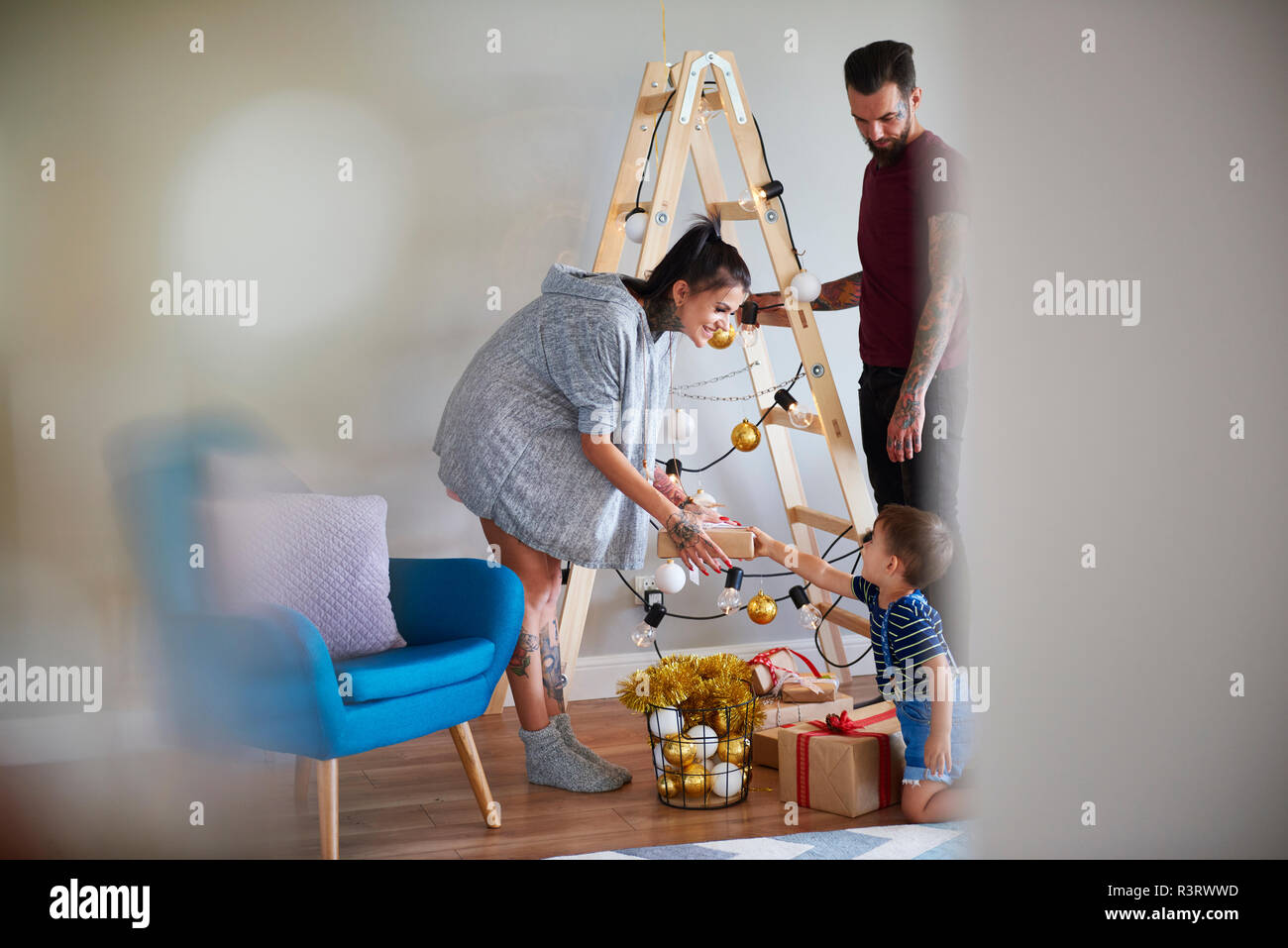 Moderne Familie zu Hause an Weihnachten mit Leiter als Weihnachtsbaum Stockfoto