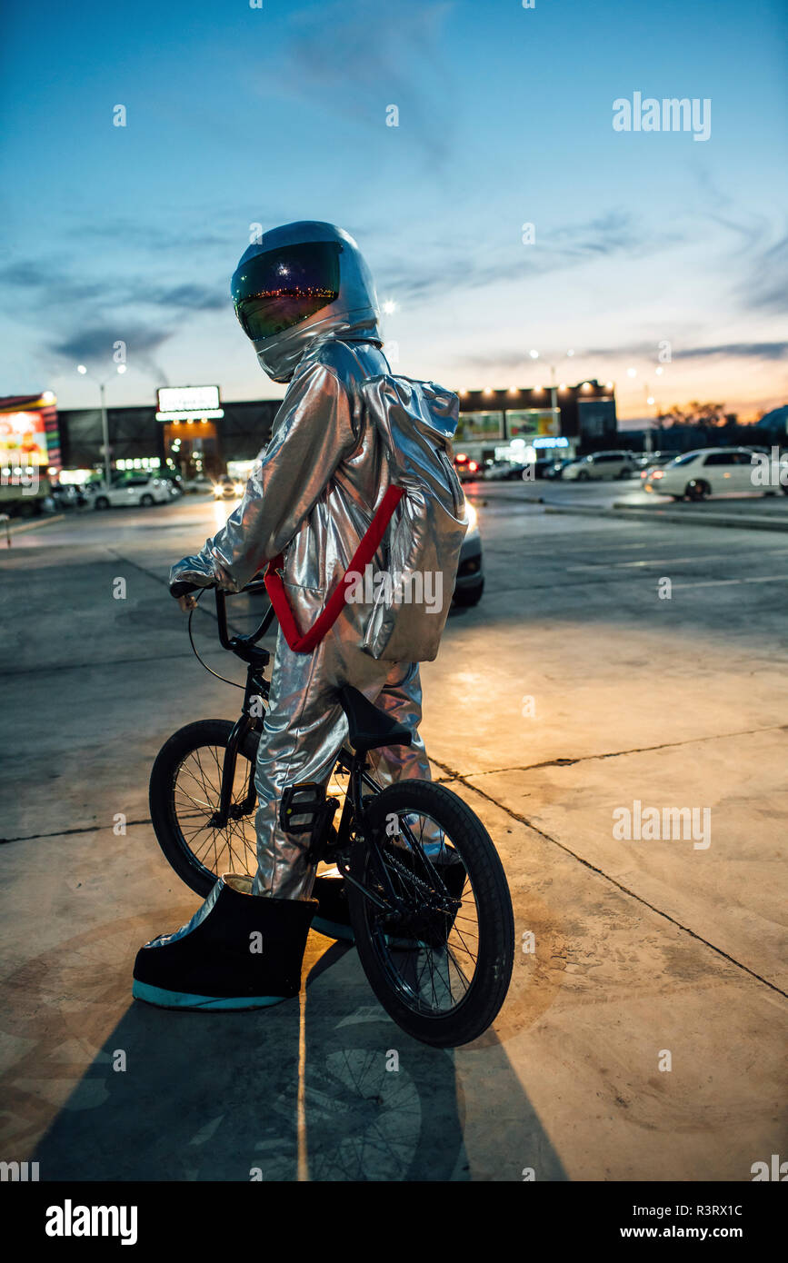 Spaceman in der Stadt in der Nacht auf Parkplatz mit BMX Bike Stockfoto