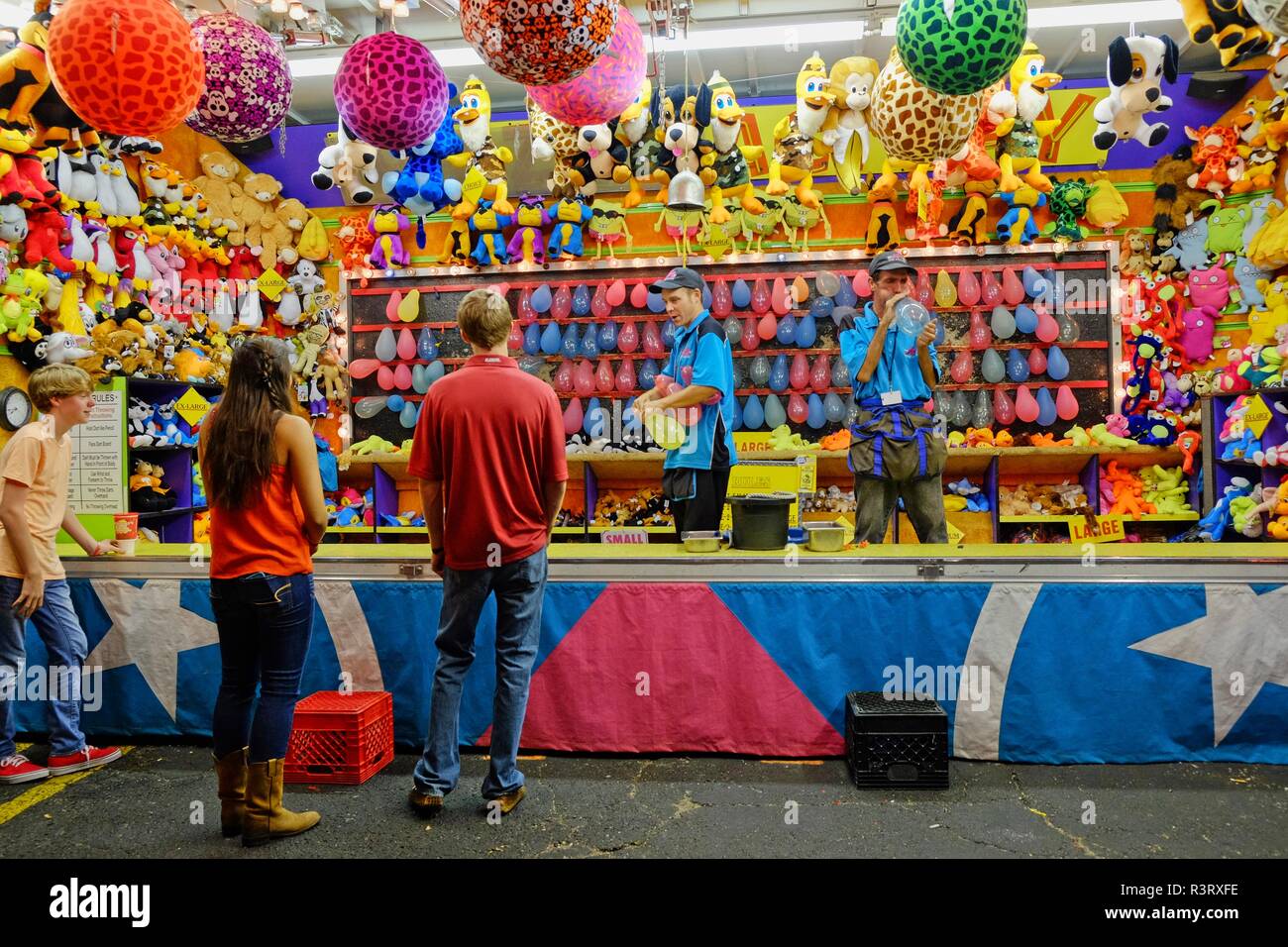Karneval Spiel stand mit kleinen Kindern und zwei Arbeiter mit Ballons und Preise an der Nationalen Messe in Montgomery Alabama, USA warten. Stockfoto