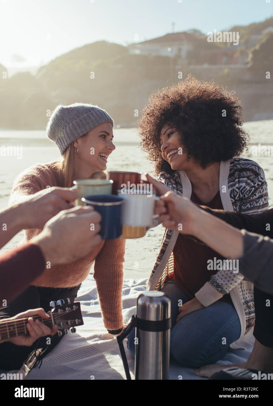 Eine Gruppe von Freunden in Party feiern mit Kaffee am Strand in Abend. Junge Menschen toasten Kaffeetassen am Strand. Stockfoto