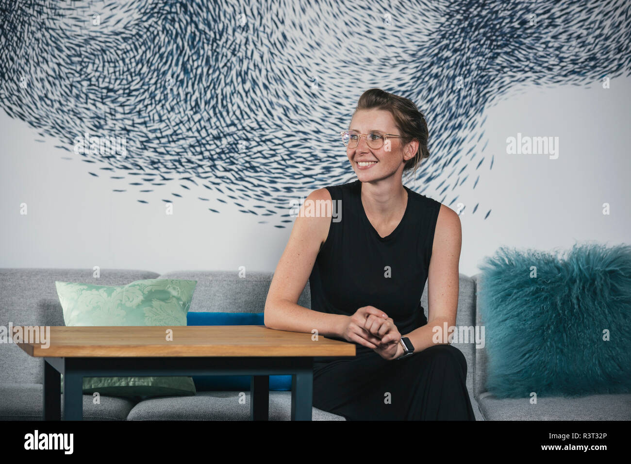 Frau sitzt in modernen Büros, lächelnd Stockfoto