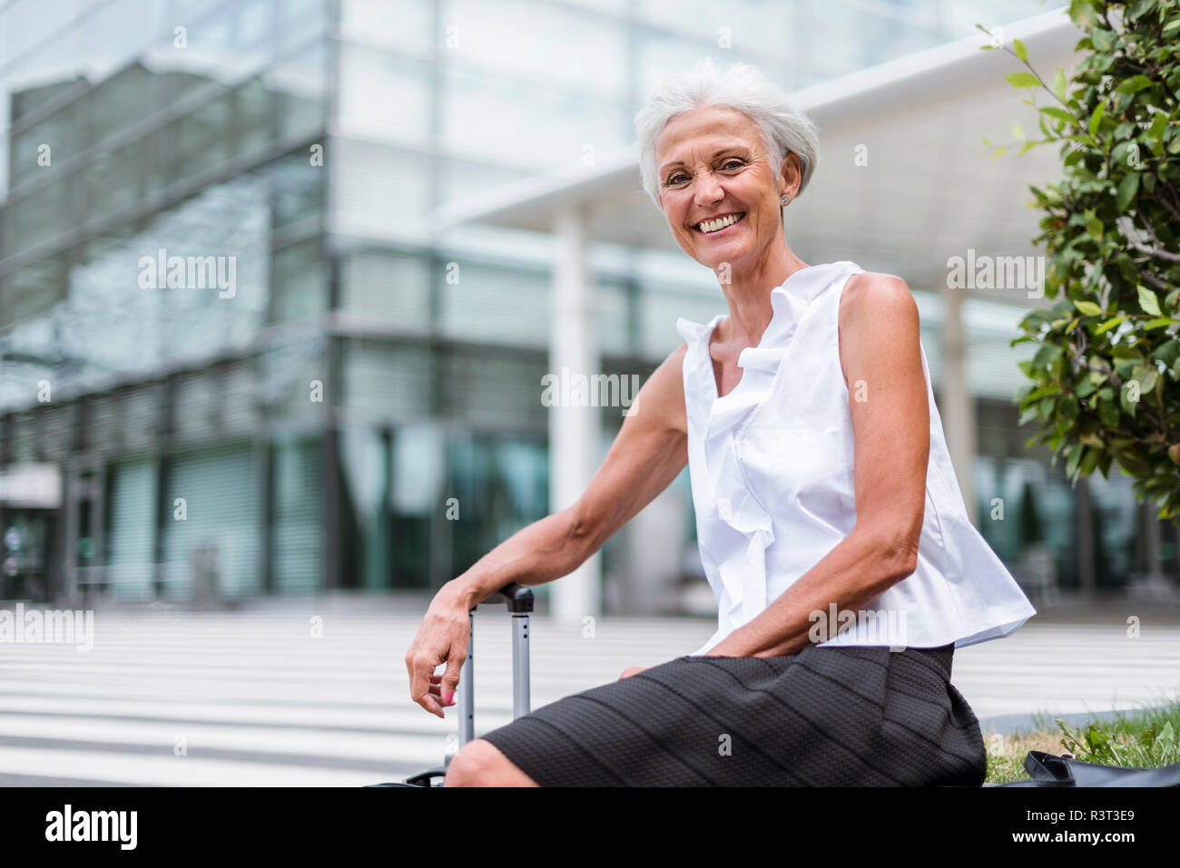 Portrait von gerne ältere Frau mit Gepäck in der Stadt sitzen Stockfoto
