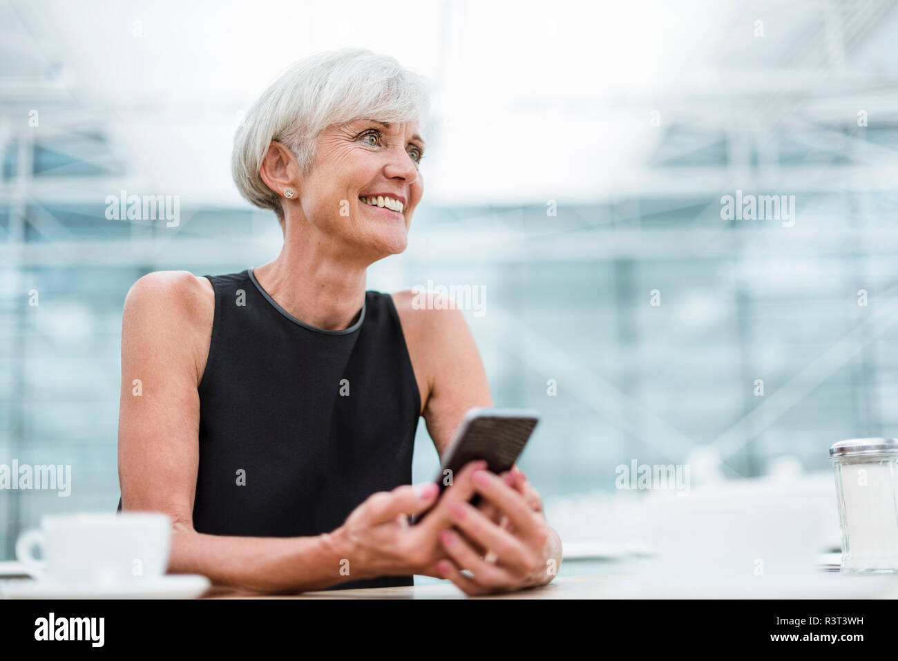 Lächelnde ältere Frau mit Handy in ein Cafe Stockfoto