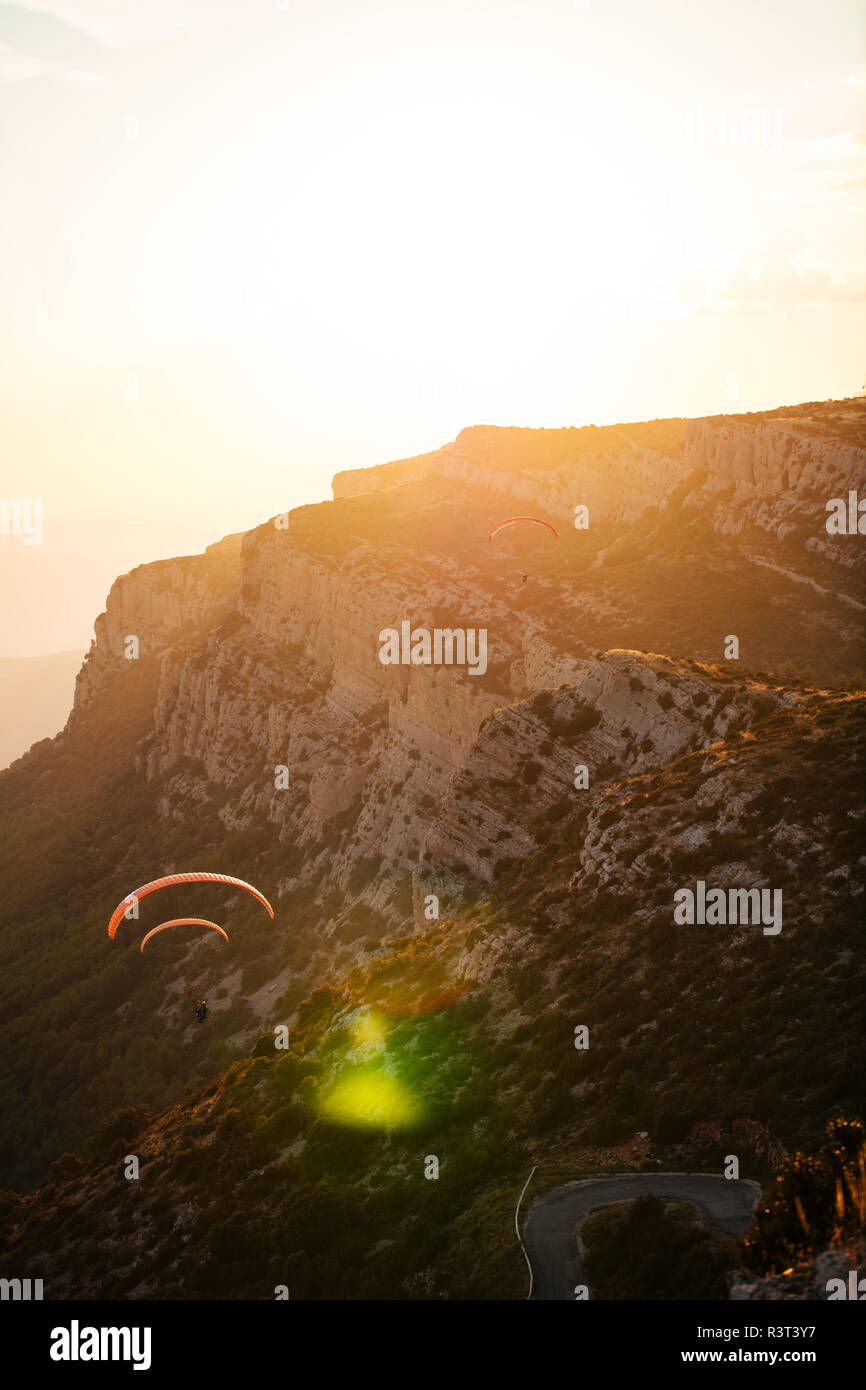 Spanien, Silhouette von Gleitschirm soaring hoch über die Berge bei Sonnenuntergang Stockfoto