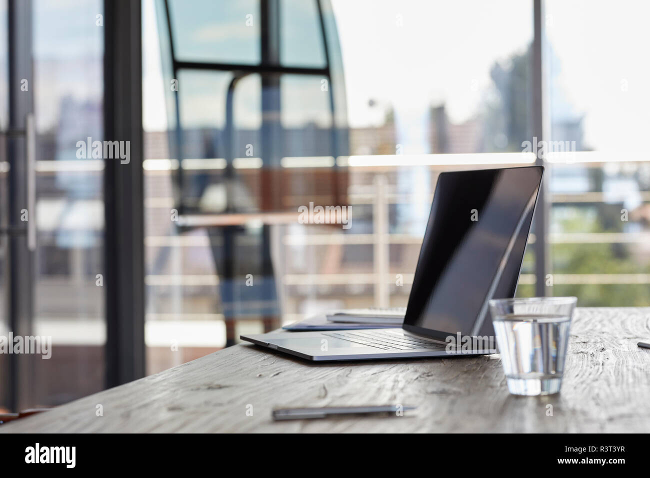 Laptop und ein Glas Wasser auf dem Schreibtisch im Büro Stockfoto