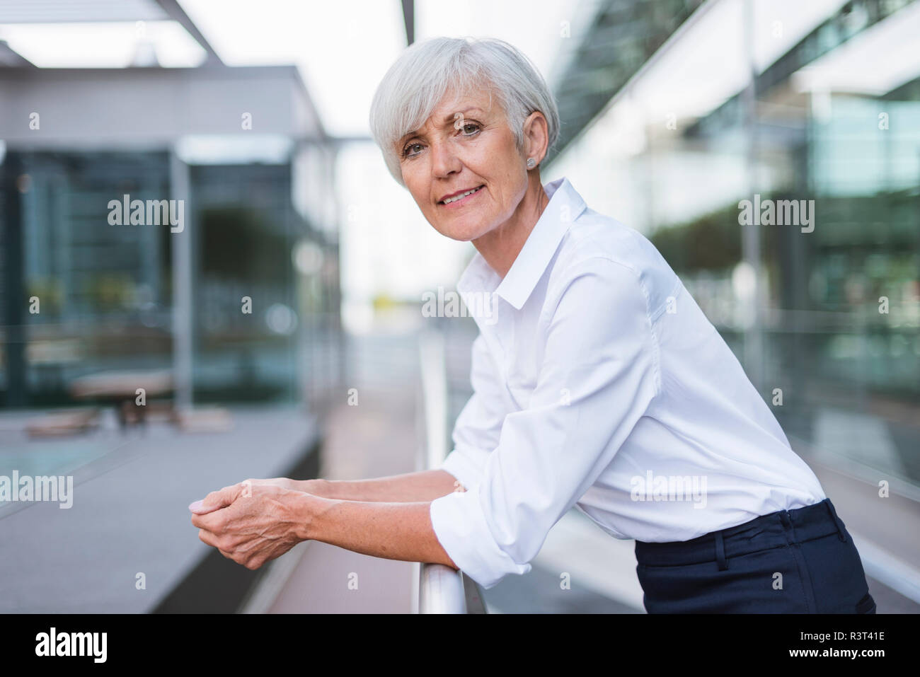 Portrait von zuversichtlich Senior Frau lehnte sich auf Geländer in der Stadt Stockfoto