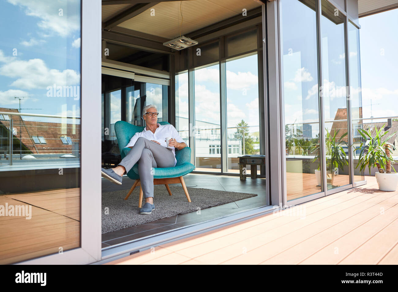 Reifer Mann im Sessel bei Dachterrasse zu Hause Stockfoto