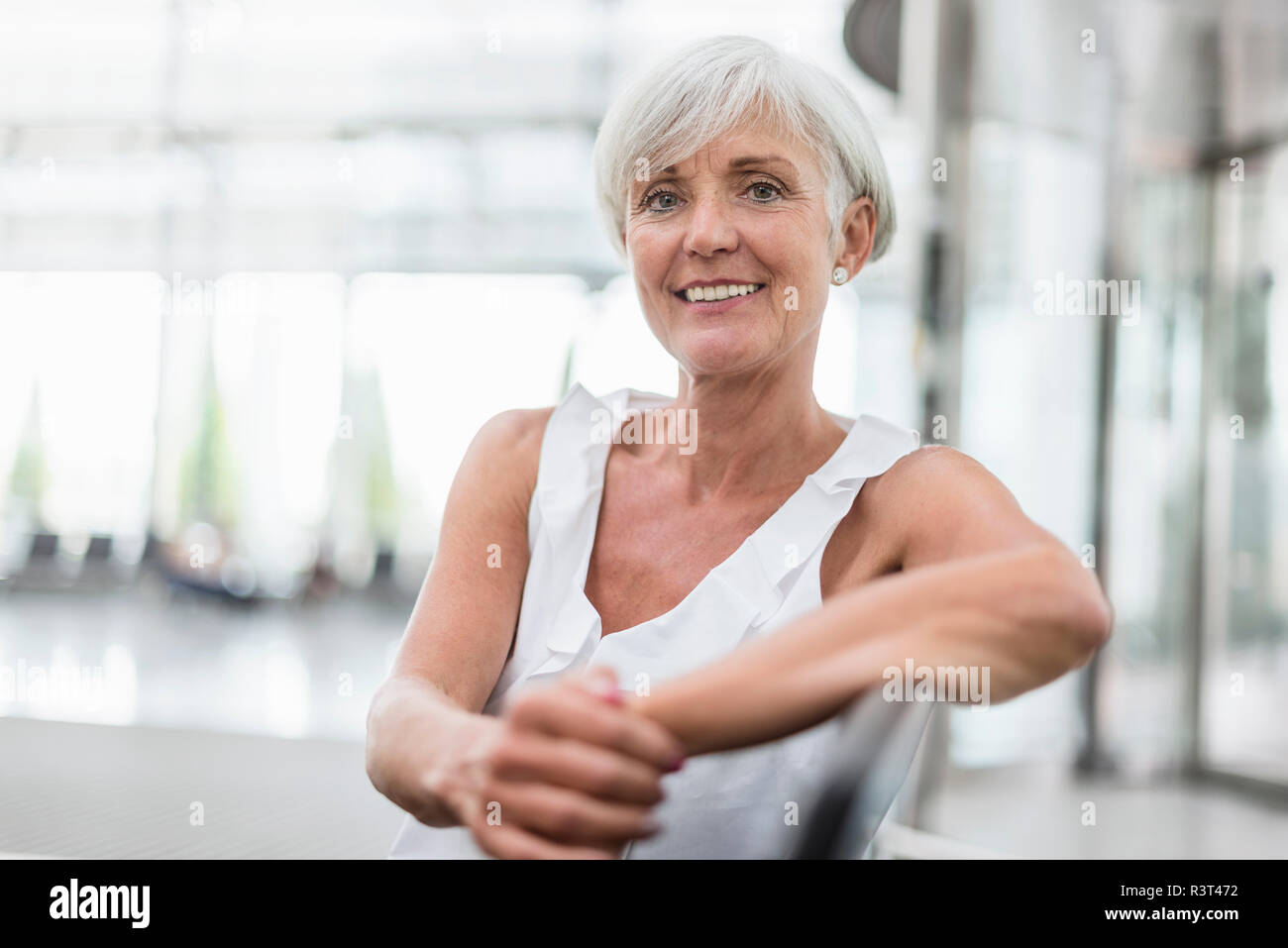 Portrait von lächelnden älteren Frau sitzt im Wartebereich Stockfoto