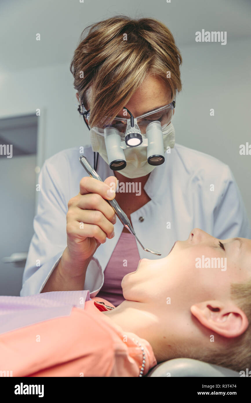 Denist Prüfung der Zähne des Jungen, mit Kopf Lupen und zahnmedizinische Instrument Stockfoto
