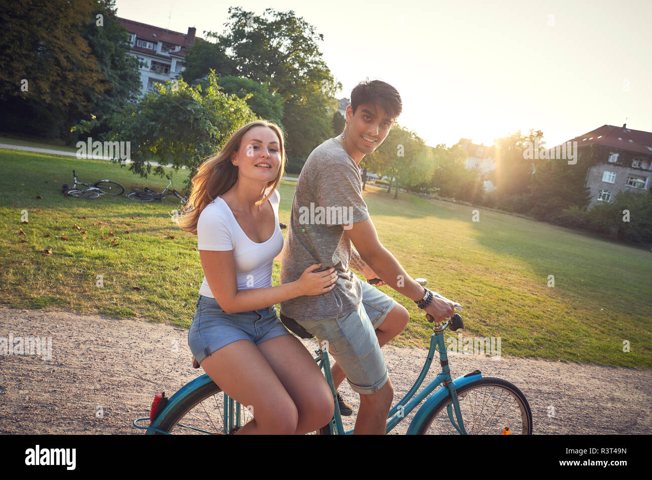 Junges Paar Reiten Fahrrad im Park, Frau sitzt auf der Zahnstange Stockfoto