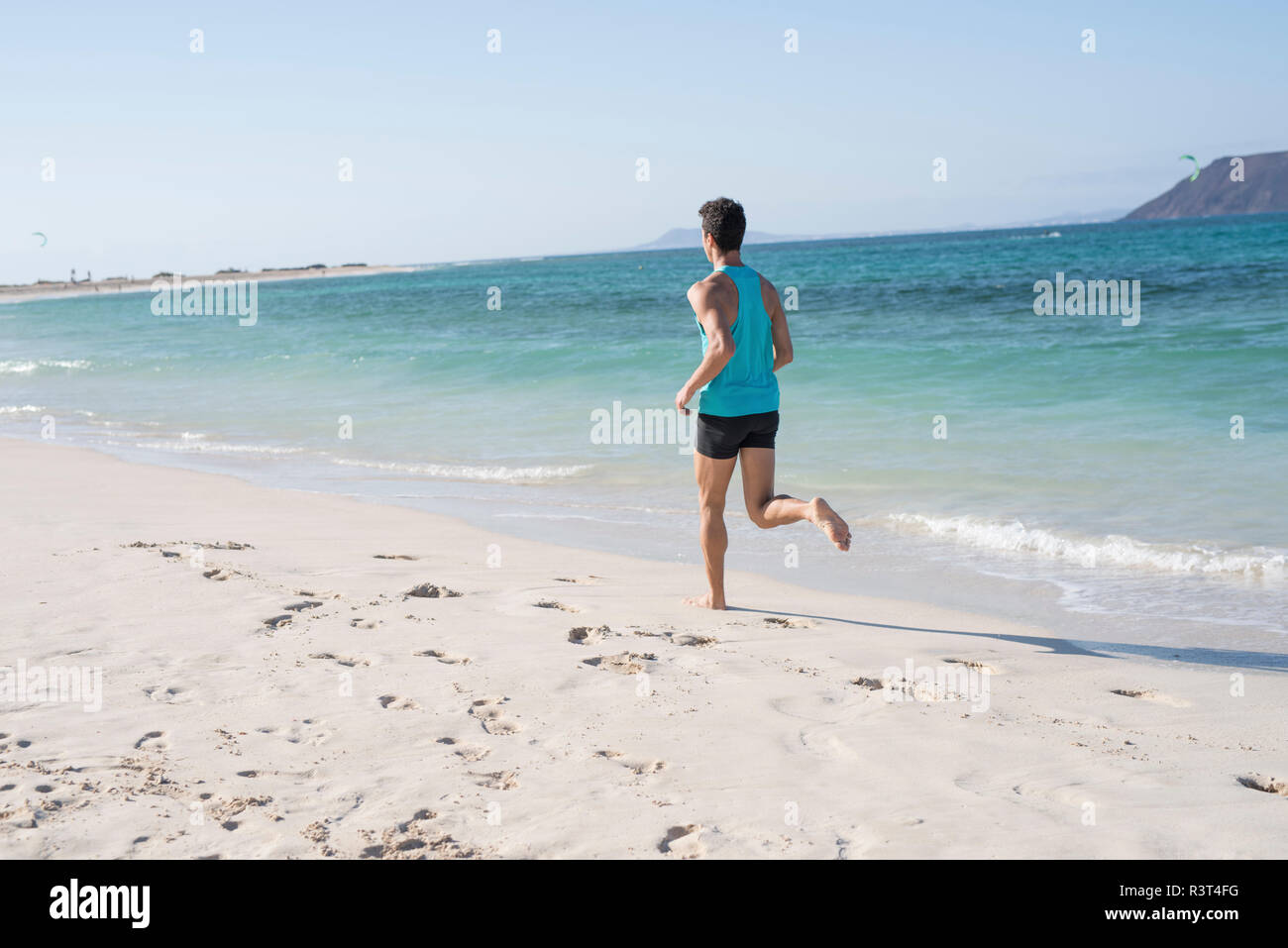Spanien, Kanarische Inseln, Fuerteventura, Rückansicht des jungen Mann laufen am Strand Stockfoto