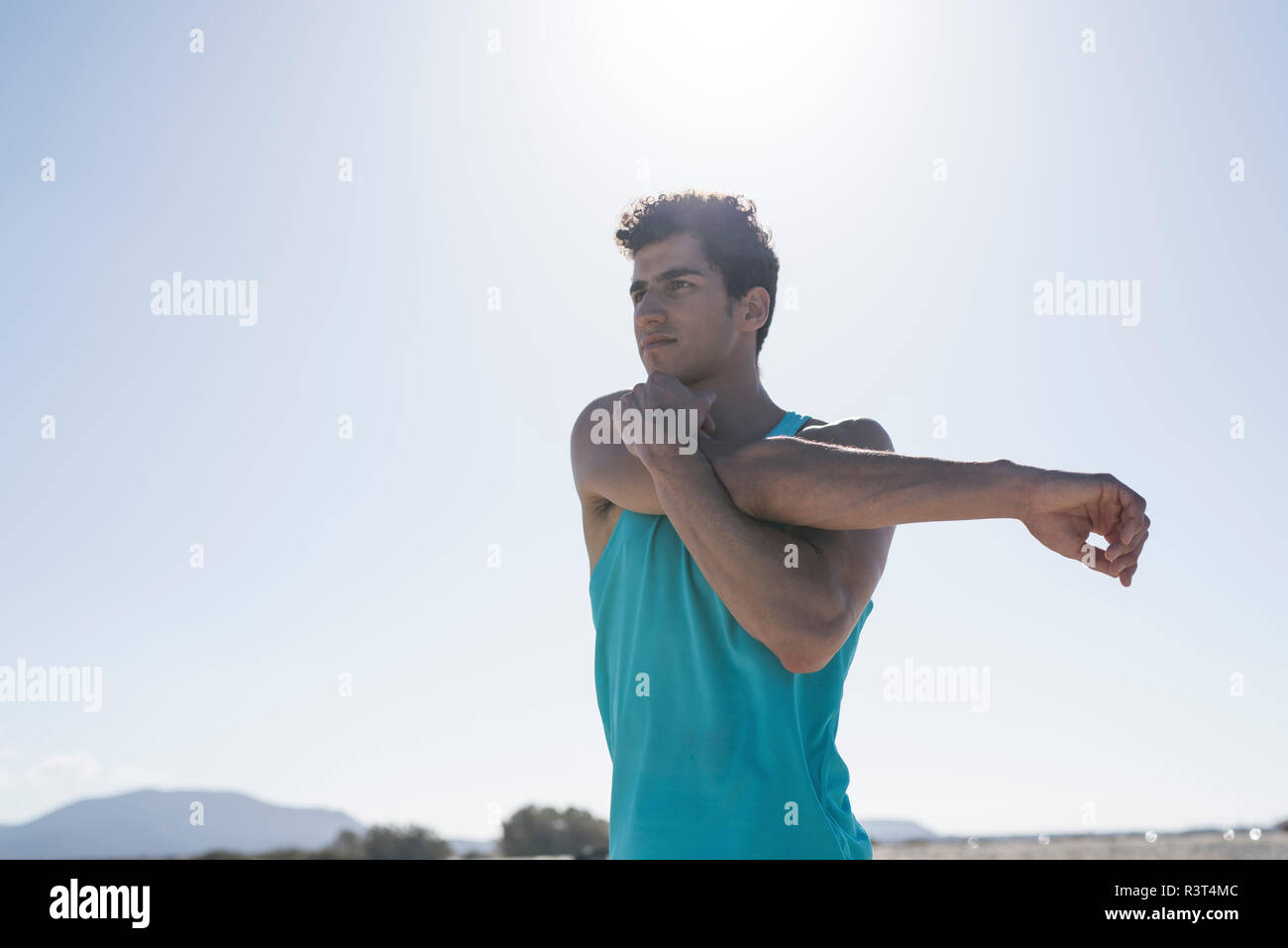 Spanien, Kanarische Inseln, Fuerteventura, junger Mann streckte seine Arm unter blauen Himmel Stockfoto