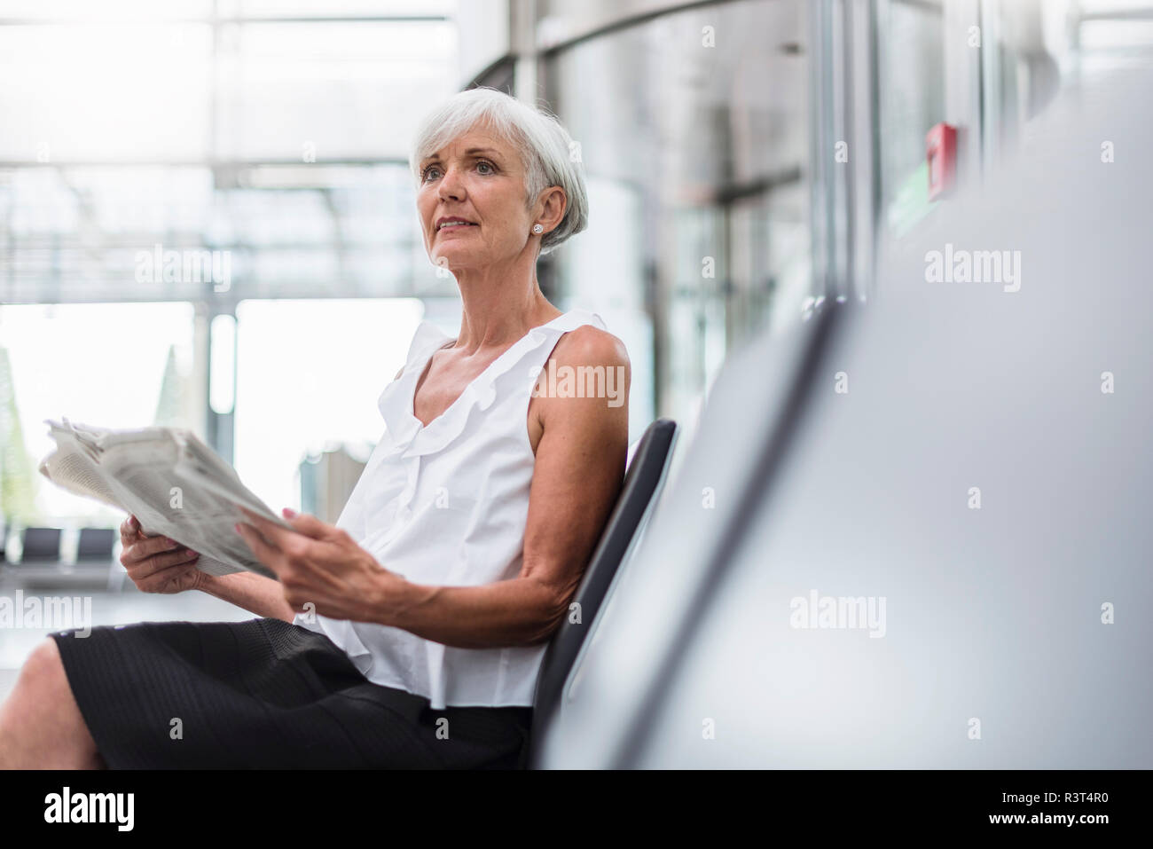 Ältere Frau im Wartebereich mit Zeitung sitzen Stockfoto