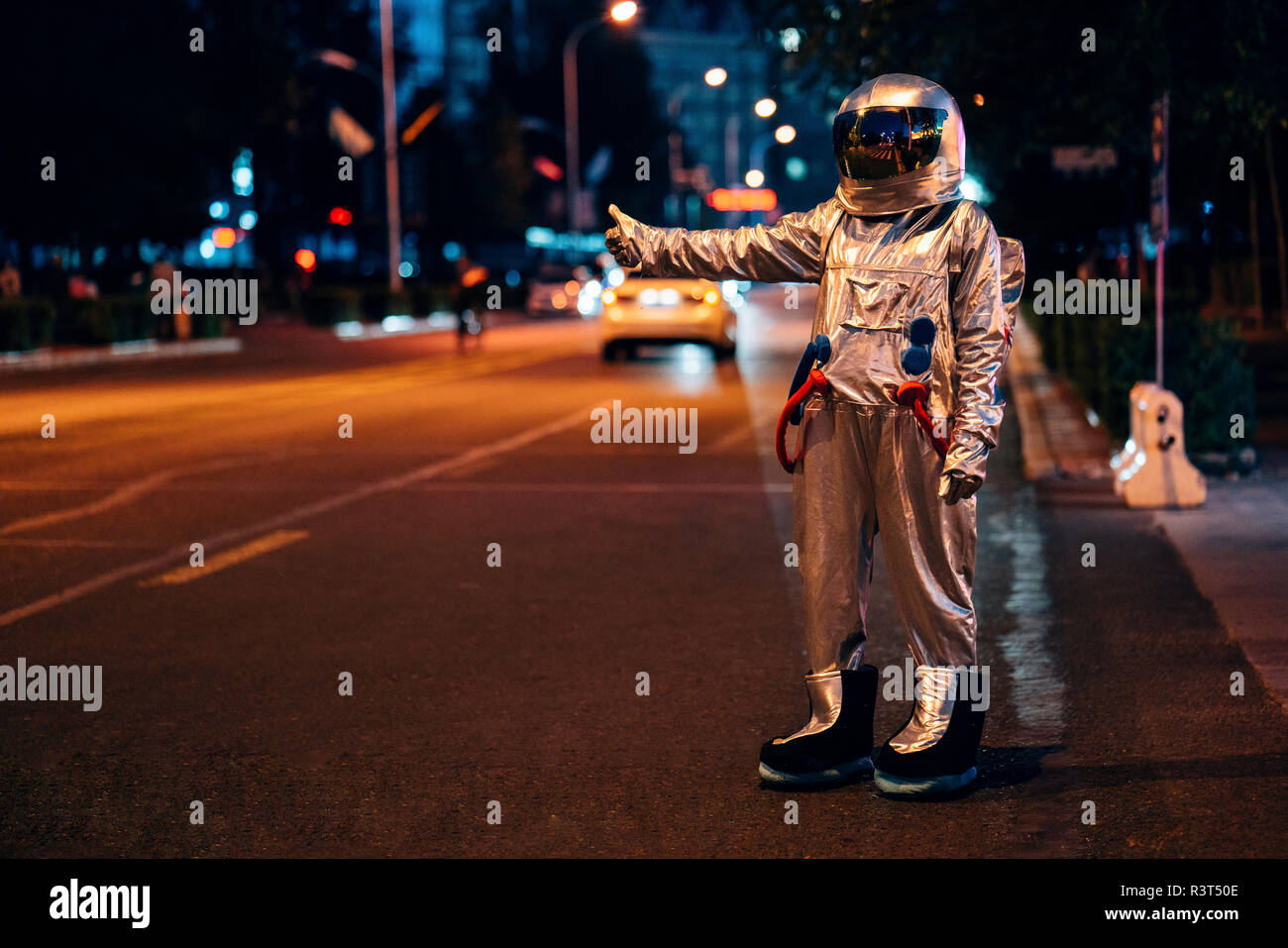 Spaceman stehen auf einer Straße in der Stadt bei Nacht per Anhalter Stockfoto