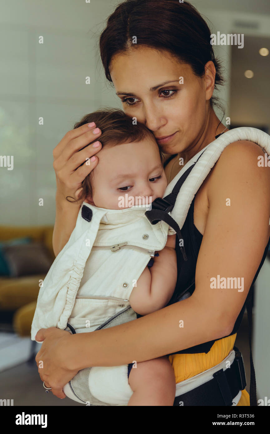 Mutter ihr Baby Mädchen in der Schlinge zu Hause tragen Stockfoto