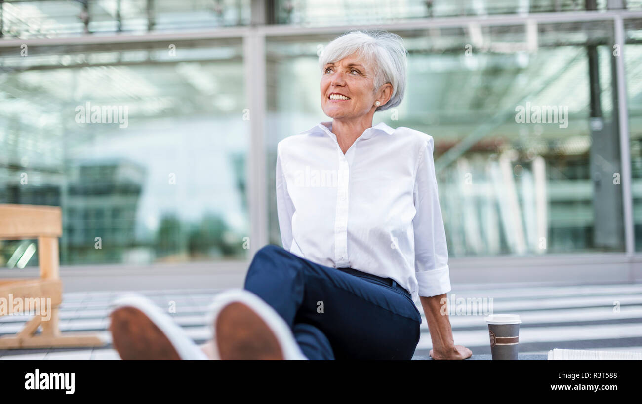 Lächelnd senior Geschäftsfrau, draußen Sitzen um das Suchen Stockfoto