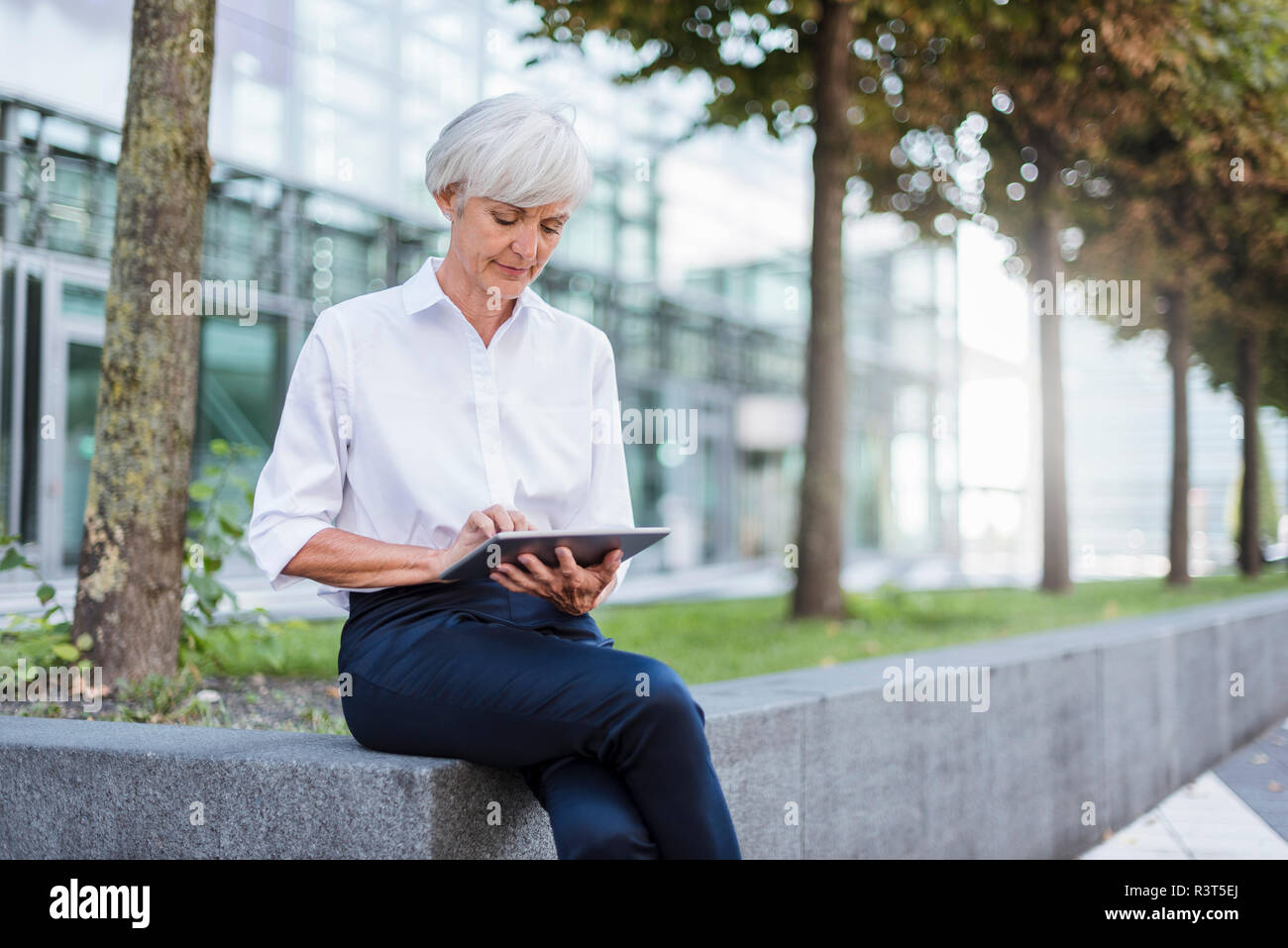 Senior Geschäftsfrau, draußen sitzen mit Tablet Stockfoto