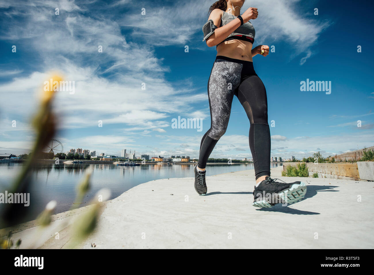 Junge athletische Frau am Flußufer läuft Stockfoto