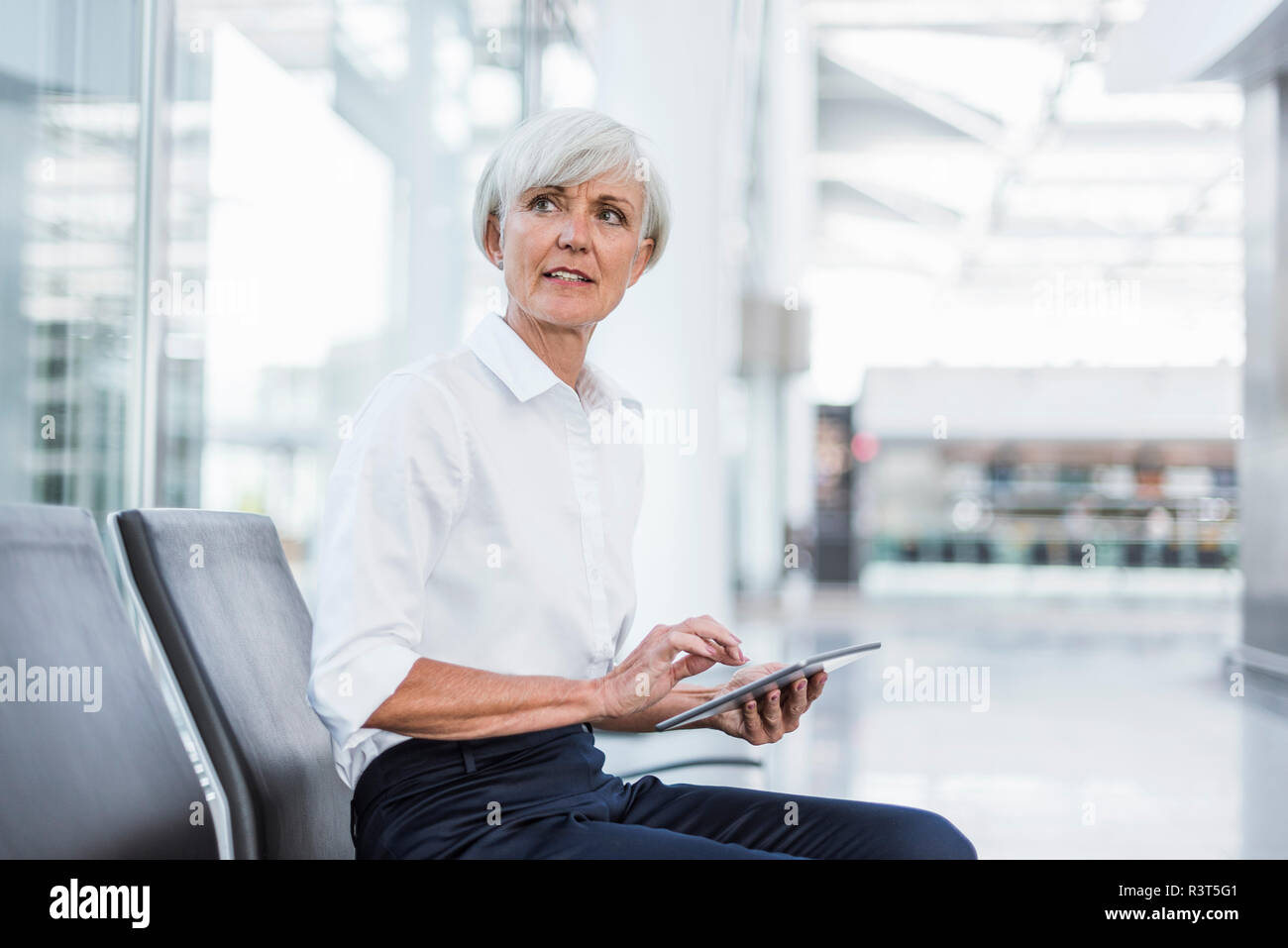 Senior Geschäftsfrau, sitzen im Wartebereich mit um Tablet suchen Stockfoto