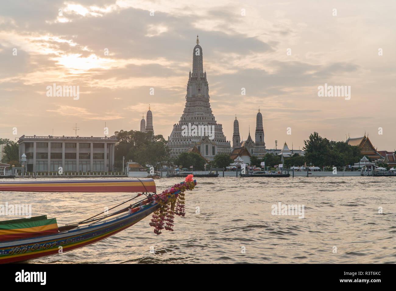 Beliebtes Touristenziel Wat Arun Tempel der Morgendämmerung über den Chao Phraya Fluss in Bangkok, Thailand bei Sonnenuntergang mit traditionellen langen Schwänzbooten Stockfoto