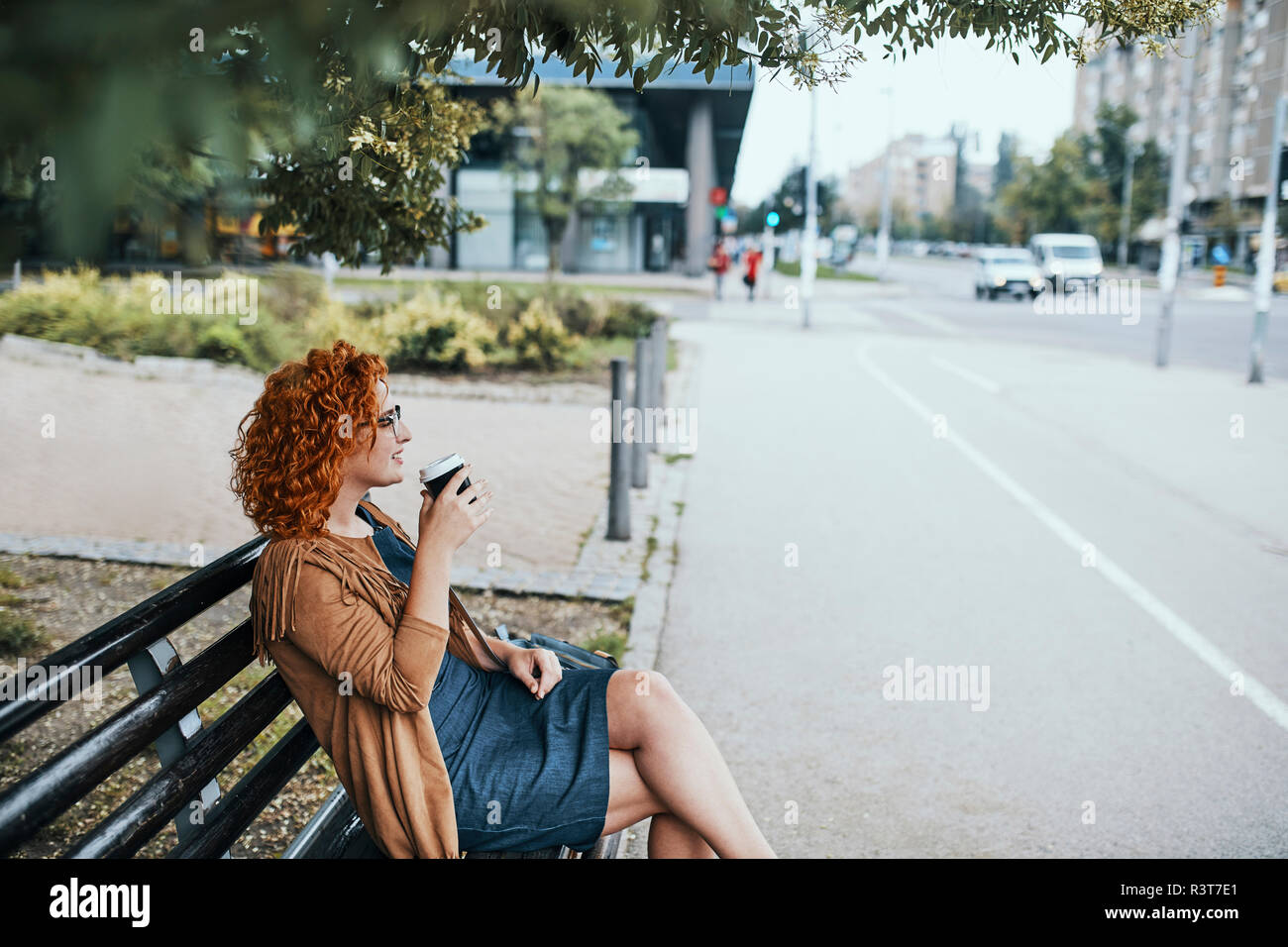 Junge Frau auf einer Bank sitzen, Kaffee trinken Stockfoto