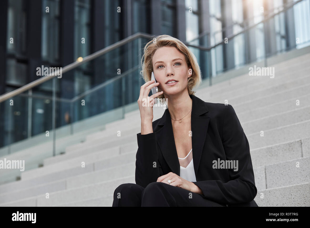 Porträt der jungen Geschäftsfrau am Telefon sitzen auf der Treppe im Freien Stockfoto
