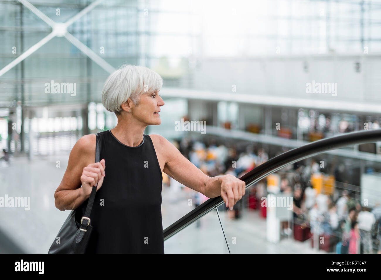 Ältere Frau auf Rolltreppe am Flughafen Stockfoto