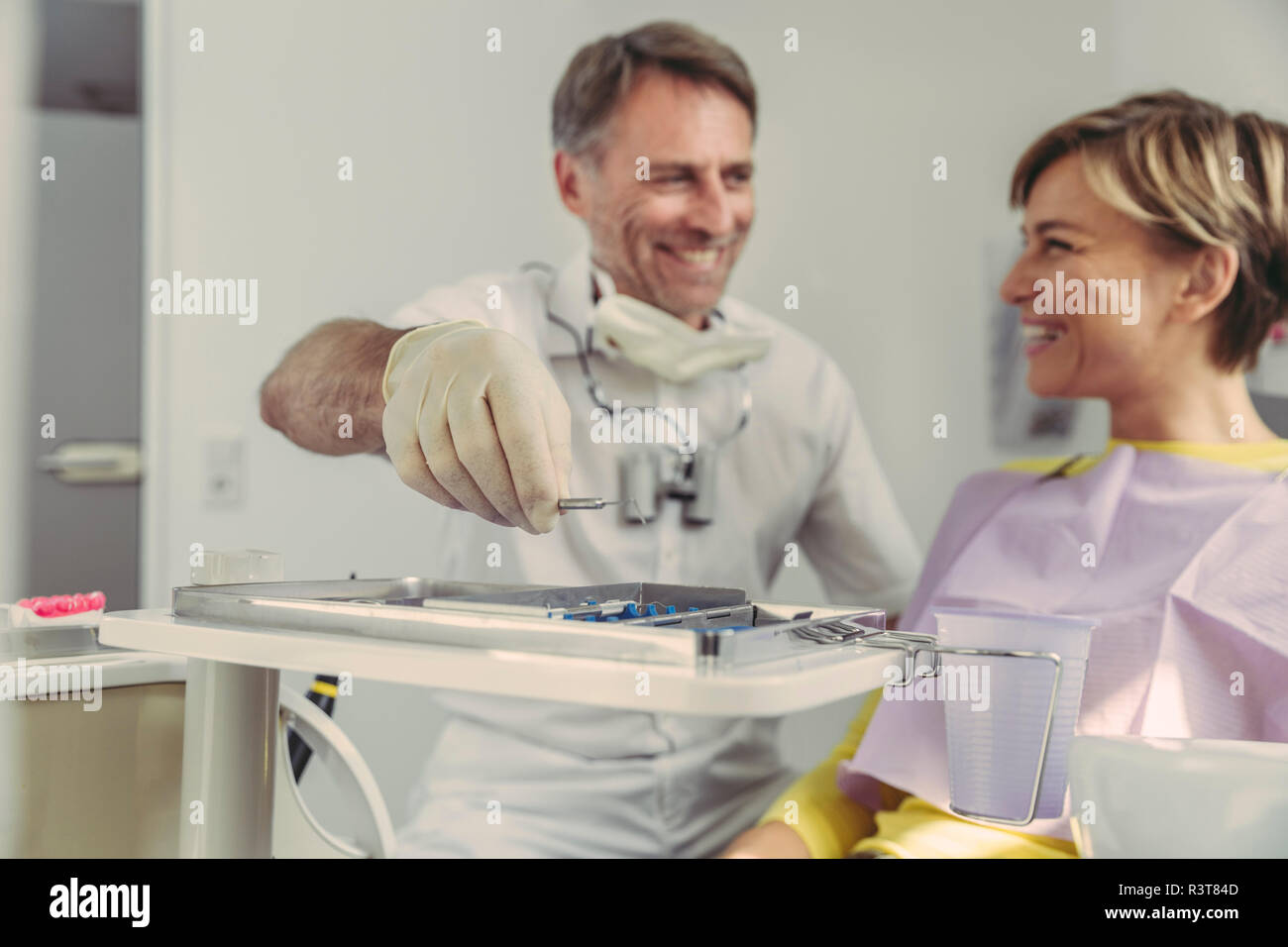 Zahnarzt setzen Instrumente auf Fach nach der Behandlung, auf seine lächelnden Patient Stockfoto