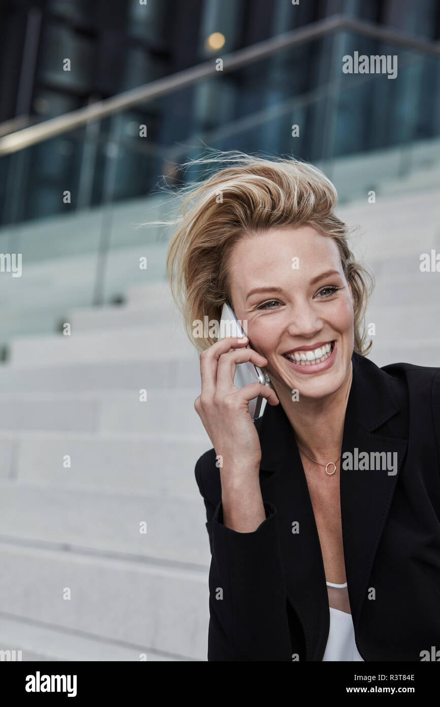Portrait von Lachen geschäftsfrau am Telefon sitzen auf der Treppe im Freien Stockfoto