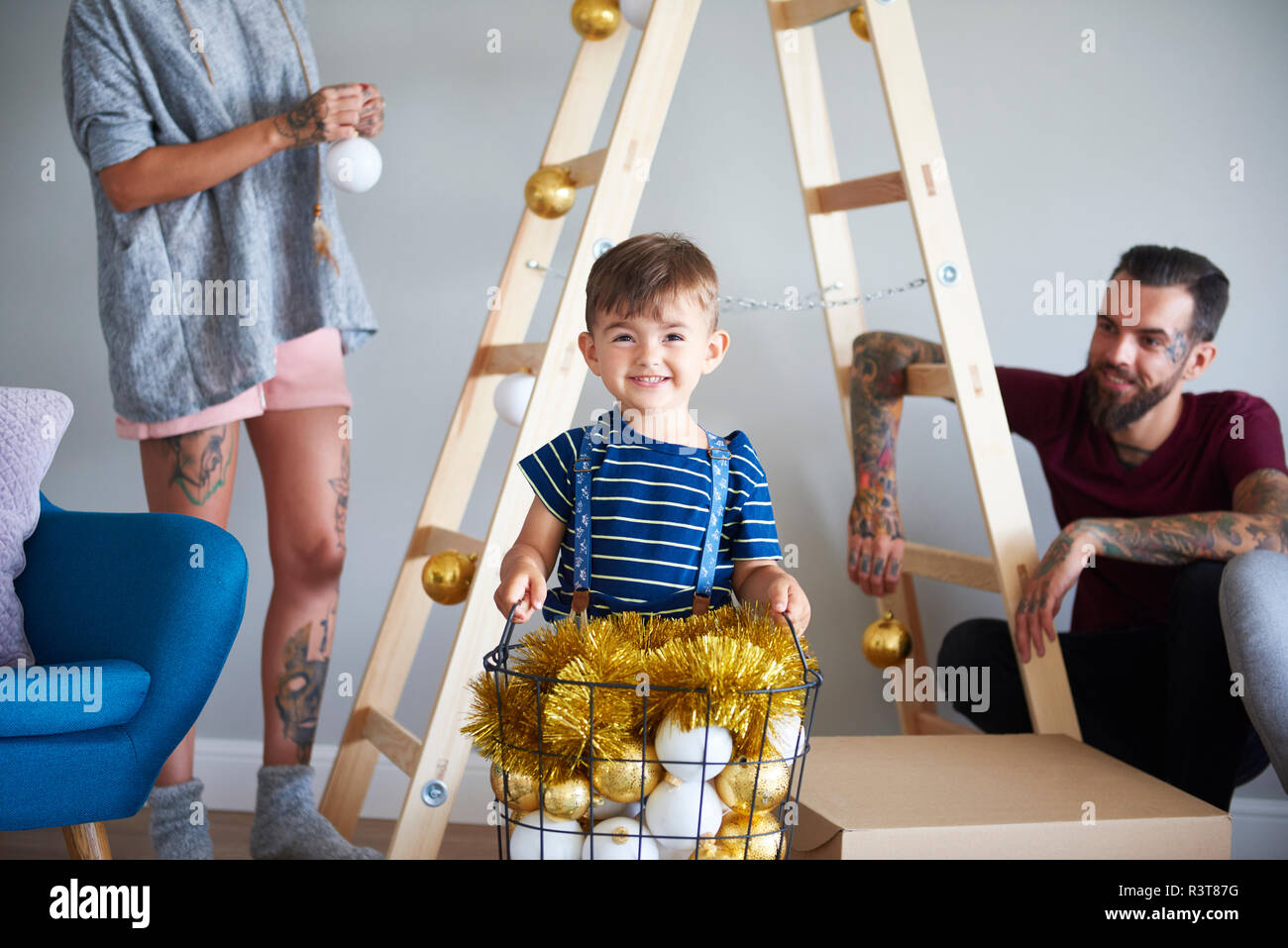 Moderne Familie dekorieren zu Hause an Weihnachten mit Leiter als Weihnachtsbaum Stockfoto