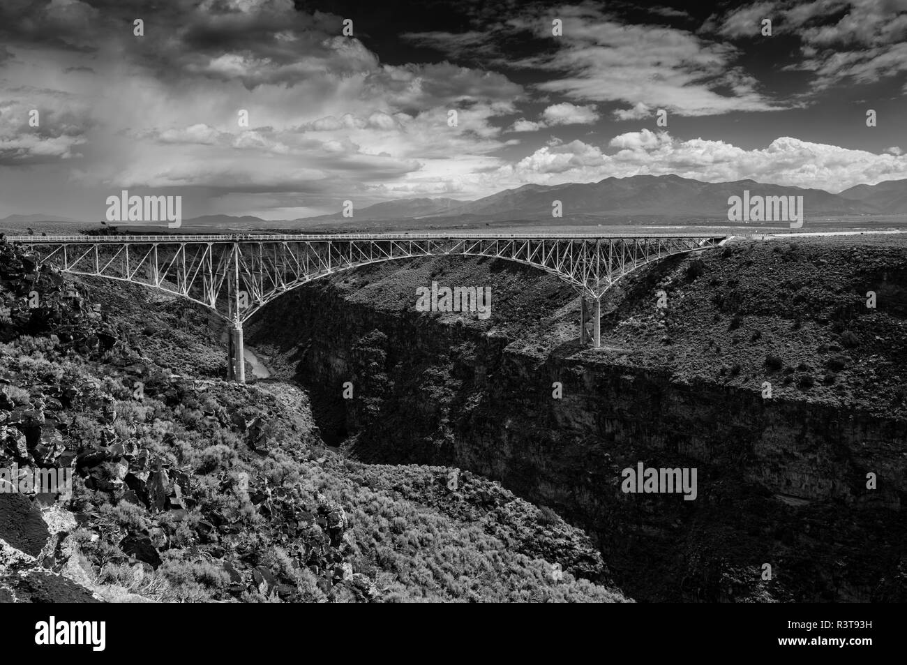 Die Brücke erstreckt sich über Rio Grande Schlucht in der Nähe von Taos, New Mexico, mit Bergen und Wetter System im Hintergrund. Stockfoto