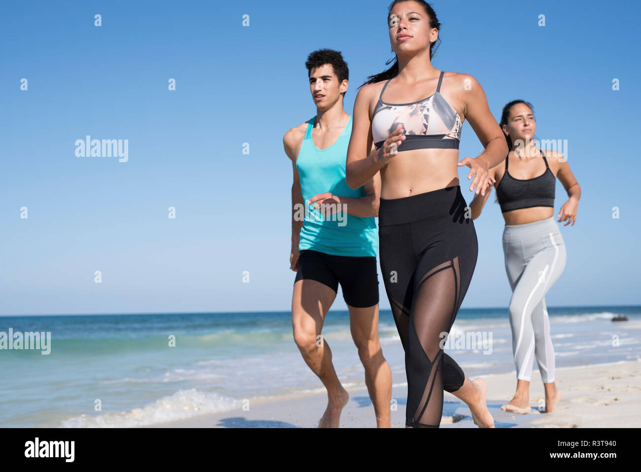 Spanien, Kanarische Inseln, Fuerteventura, zwei junge Frauen und ein junger Mann, der auf den Strand Stockfoto