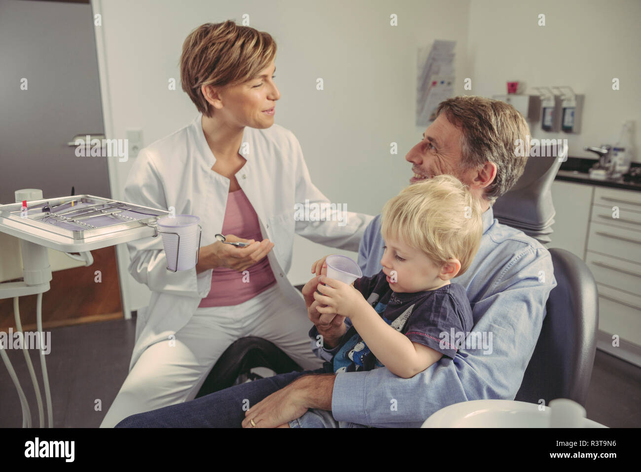 Weiblichen Zahnarzt zu sprechen Patienten mit Sohn sitzen auf seinen Schoß. Stockfoto