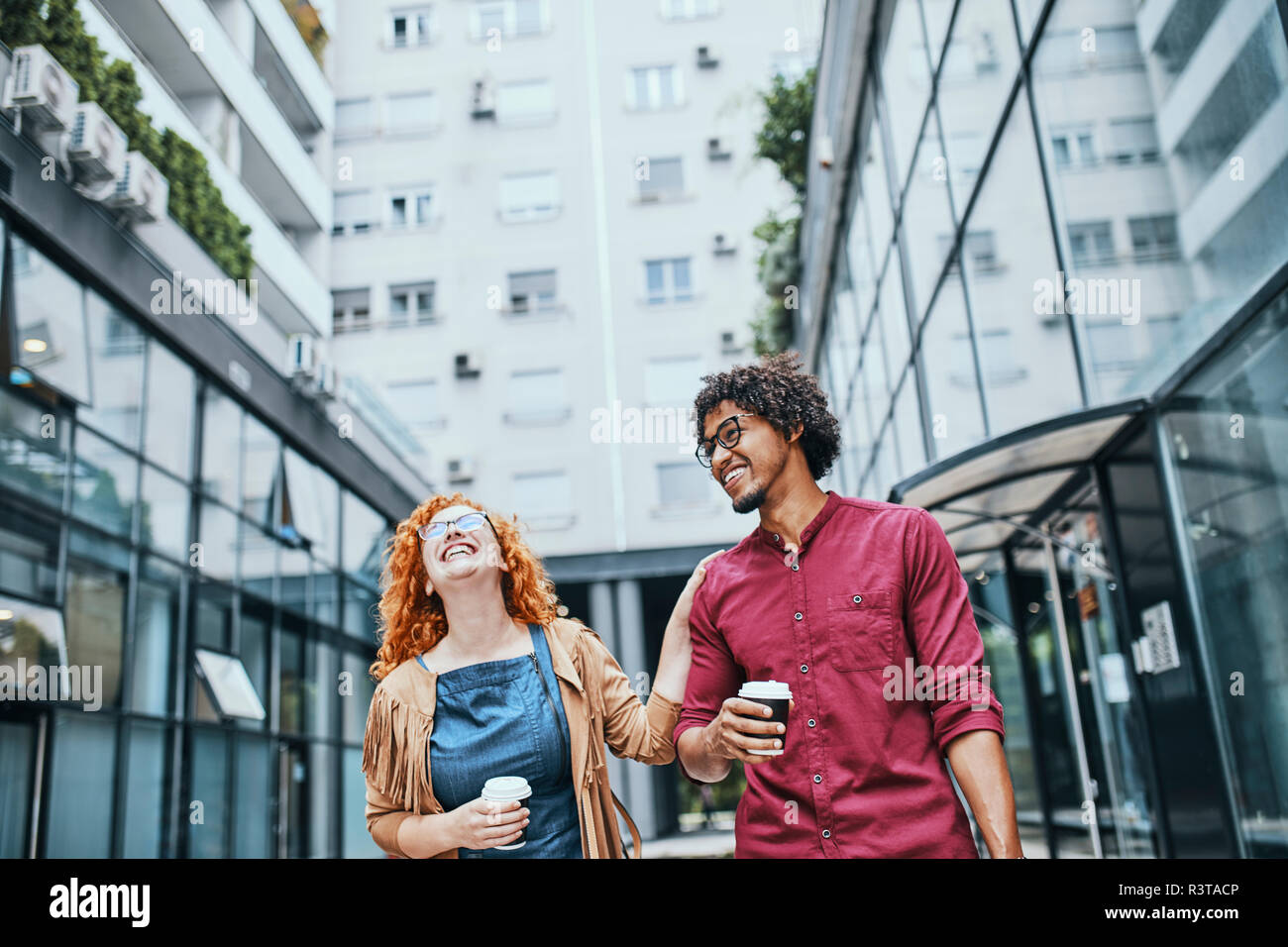 Kollegen gemeinsam zu Fuß in der Stadt, Frau trinkt Kaffee Stockfoto