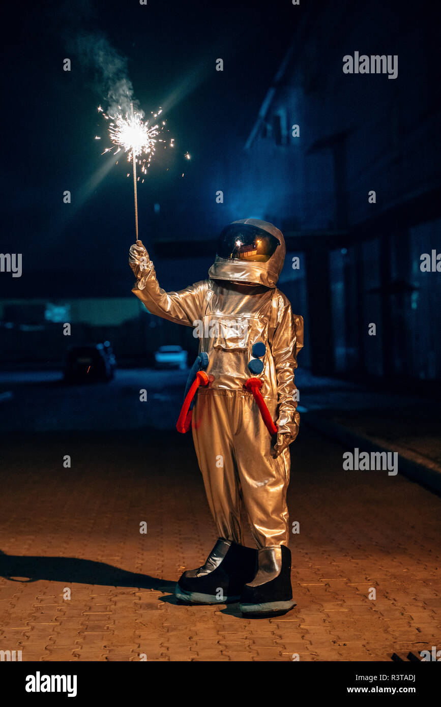 Spaceman stehen draußen in der Nacht holding Sparkler Stockfoto