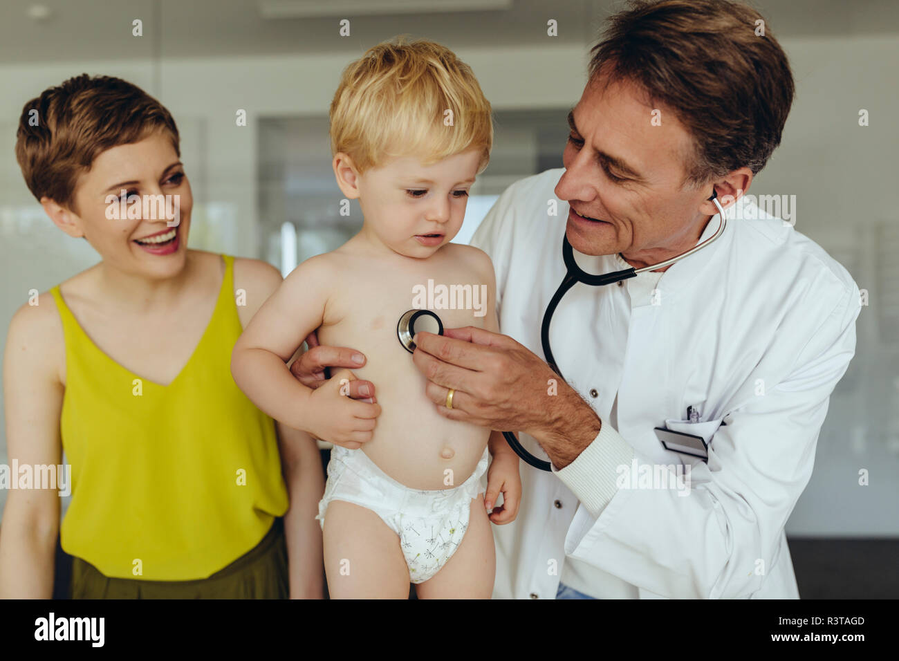 Kinderarzt untersuchen Toddler mit Stethoskop, Mutter steht neben Ihnen Stockfoto