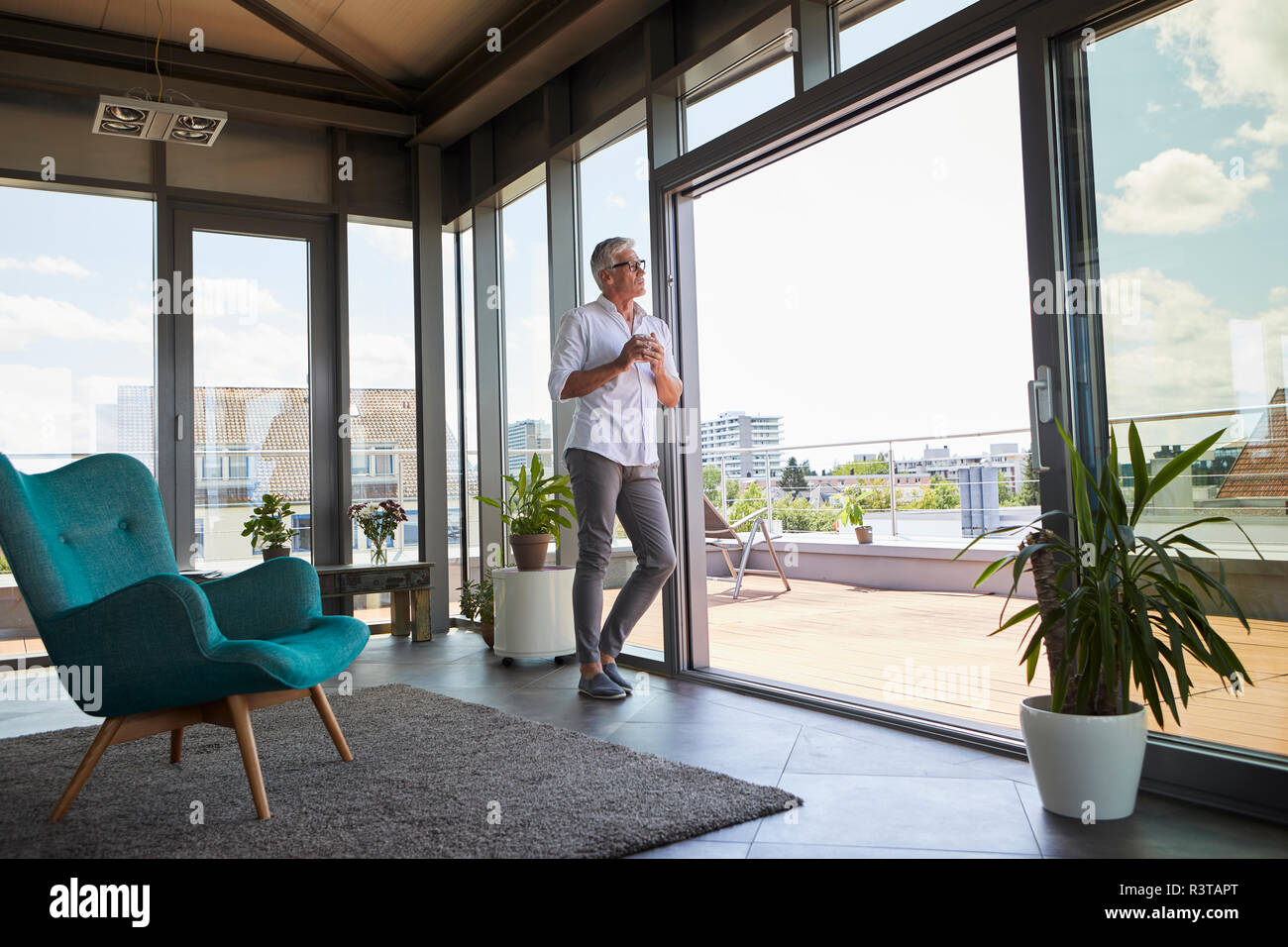 Nachdenklich reifer Mann mit Kaffeetasse stand am Fenster zu Hause Stockfoto