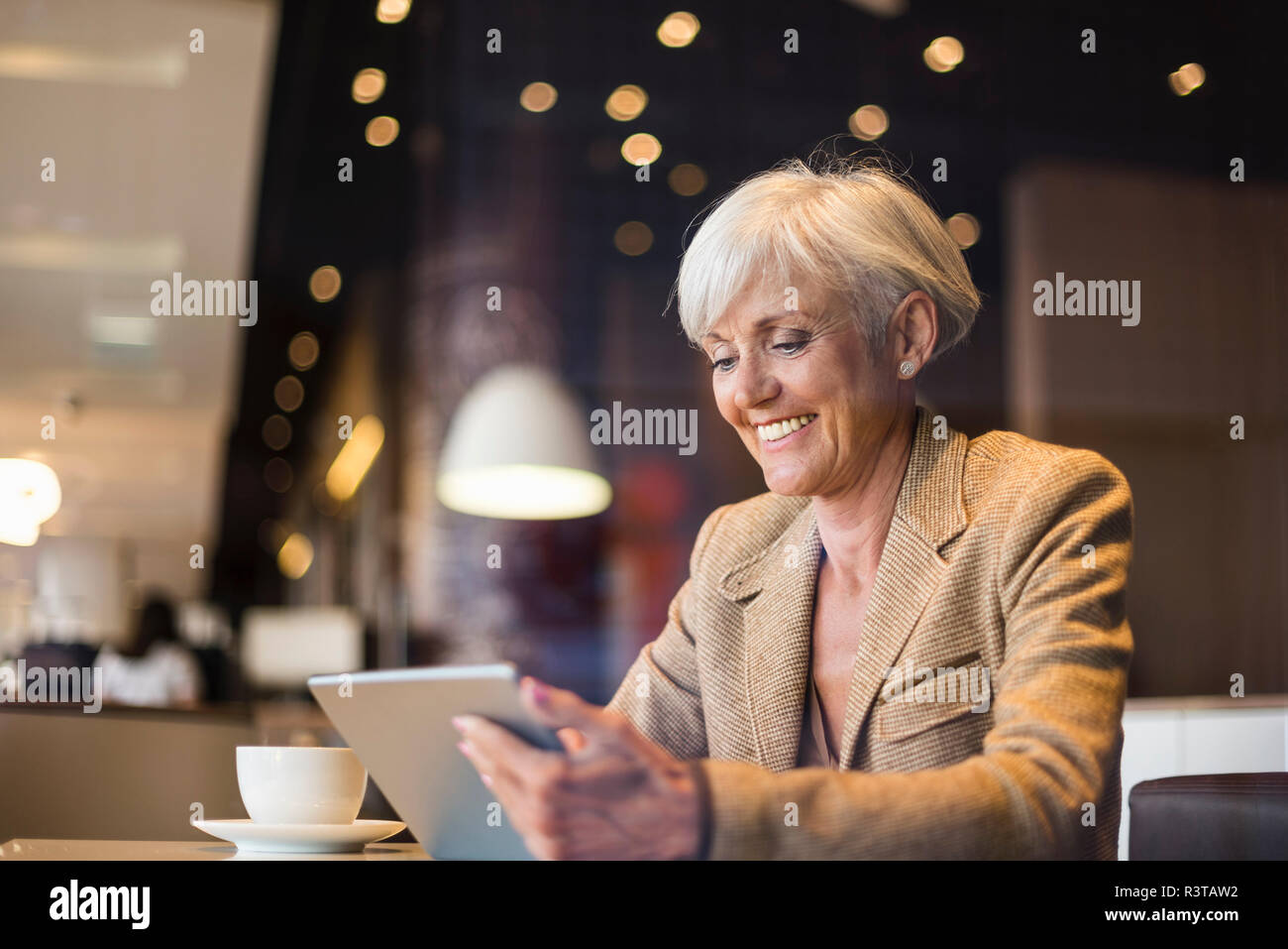 Lächelnd senior Geschäftsfrau mit Tablette in ein Cafe Stockfoto
