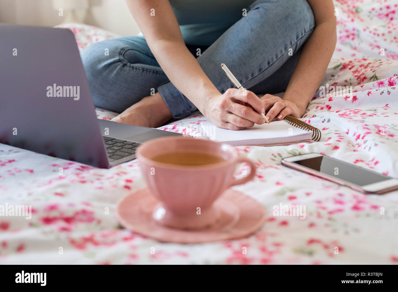 Frau sitzt auf dem Bett zu Hause arbeiten mit Laptop, Teilansicht Stockfoto