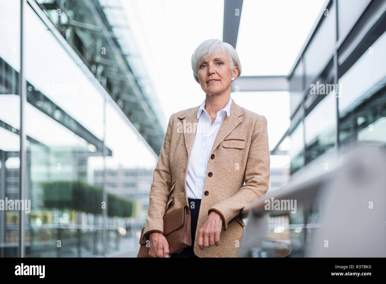Portrait von zuversichtlich senior Geschäftsfrau, lehnend auf Geländer in der Stadt Stockfoto