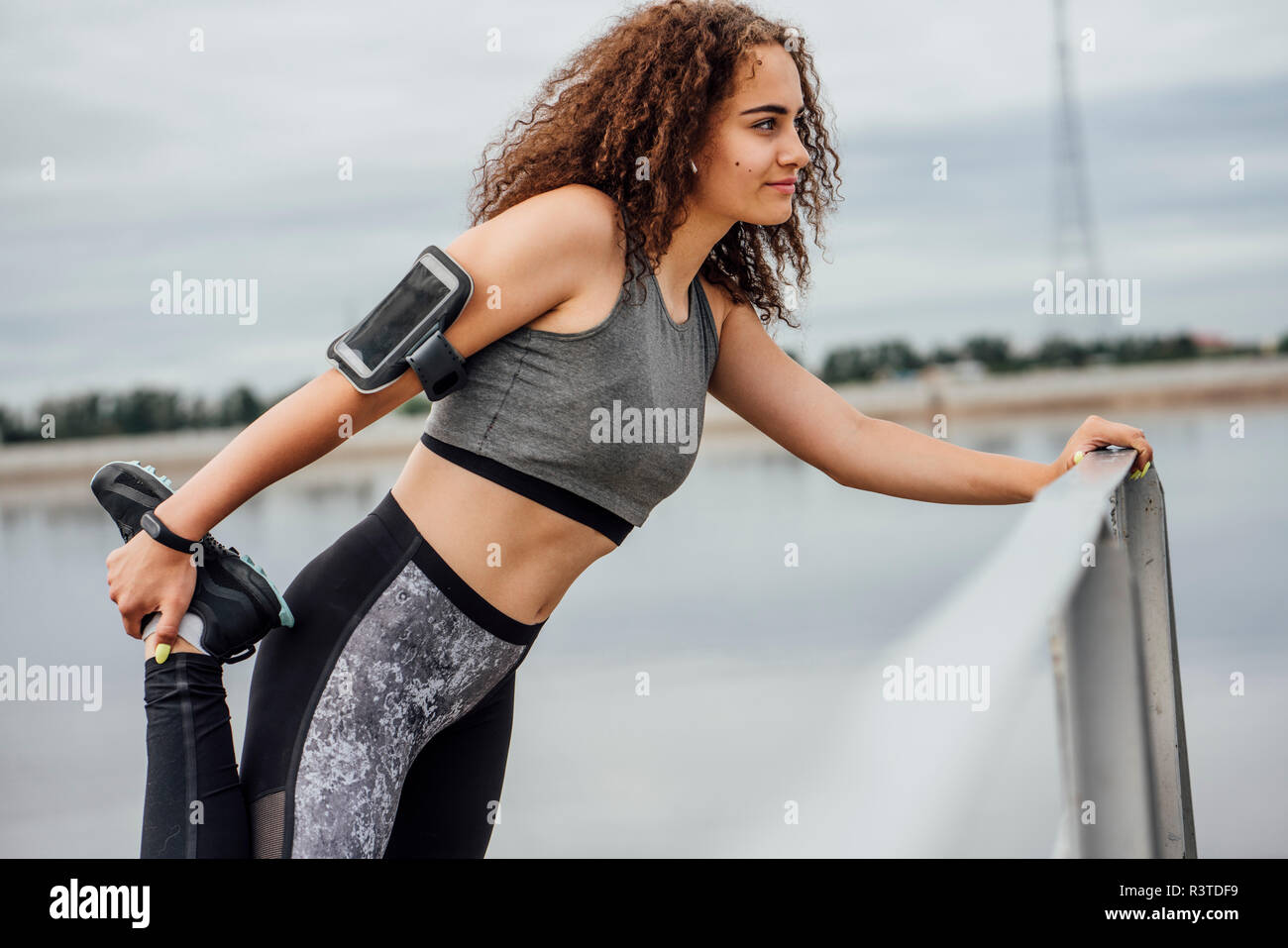 Junge athletische Frau stretching am Flußufer Stockfoto