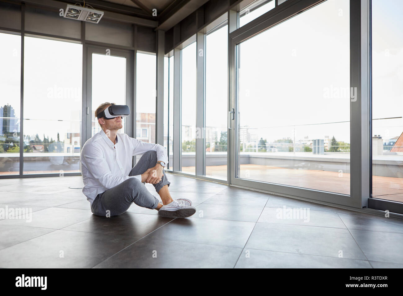 Geschäftsmann sitzt im leeren Raum VR-Brille tragen Stockfoto