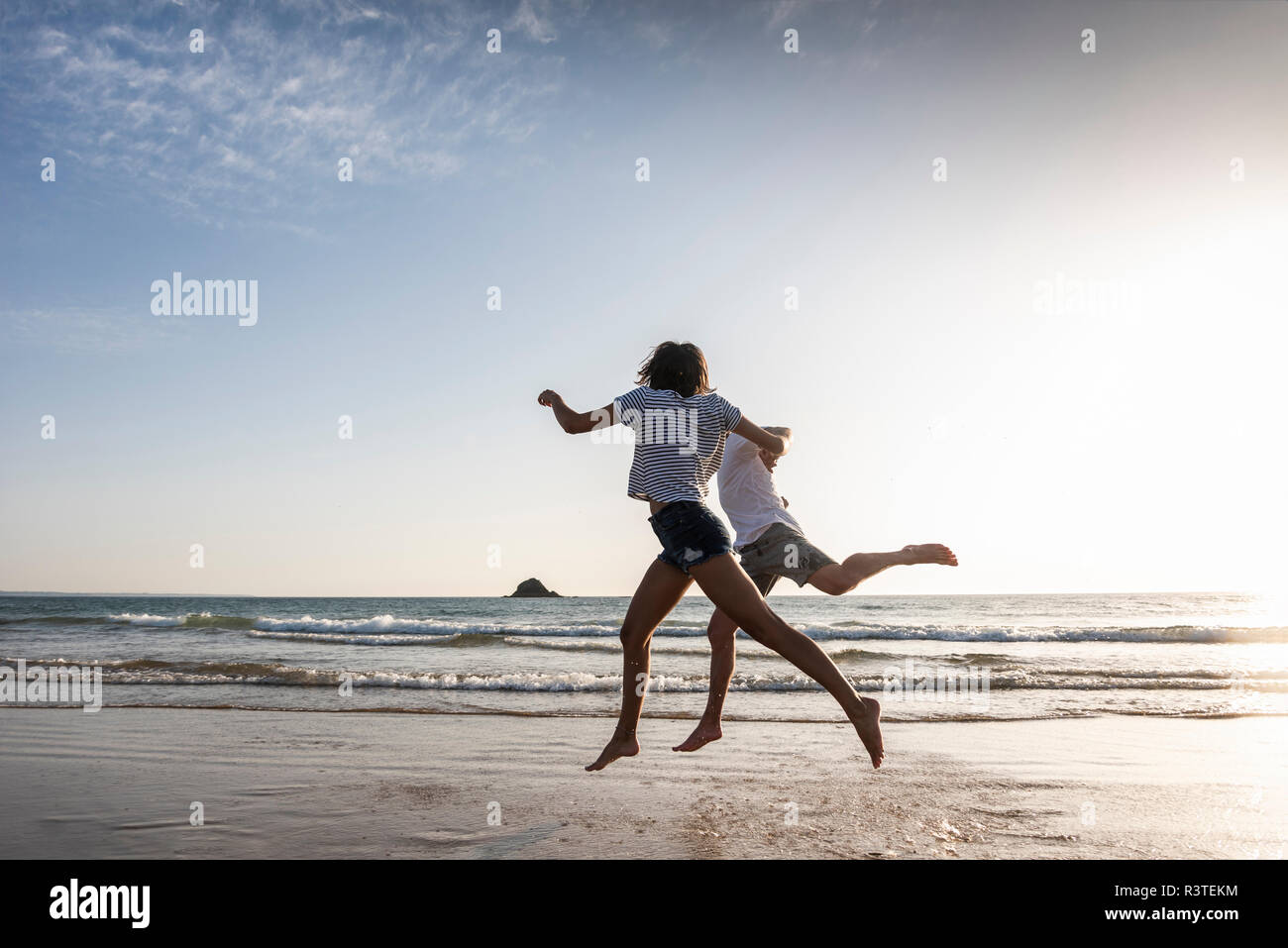 Ein junges Paar, das Spaß am Strand, Laufen und Springen am Meer Stockfoto