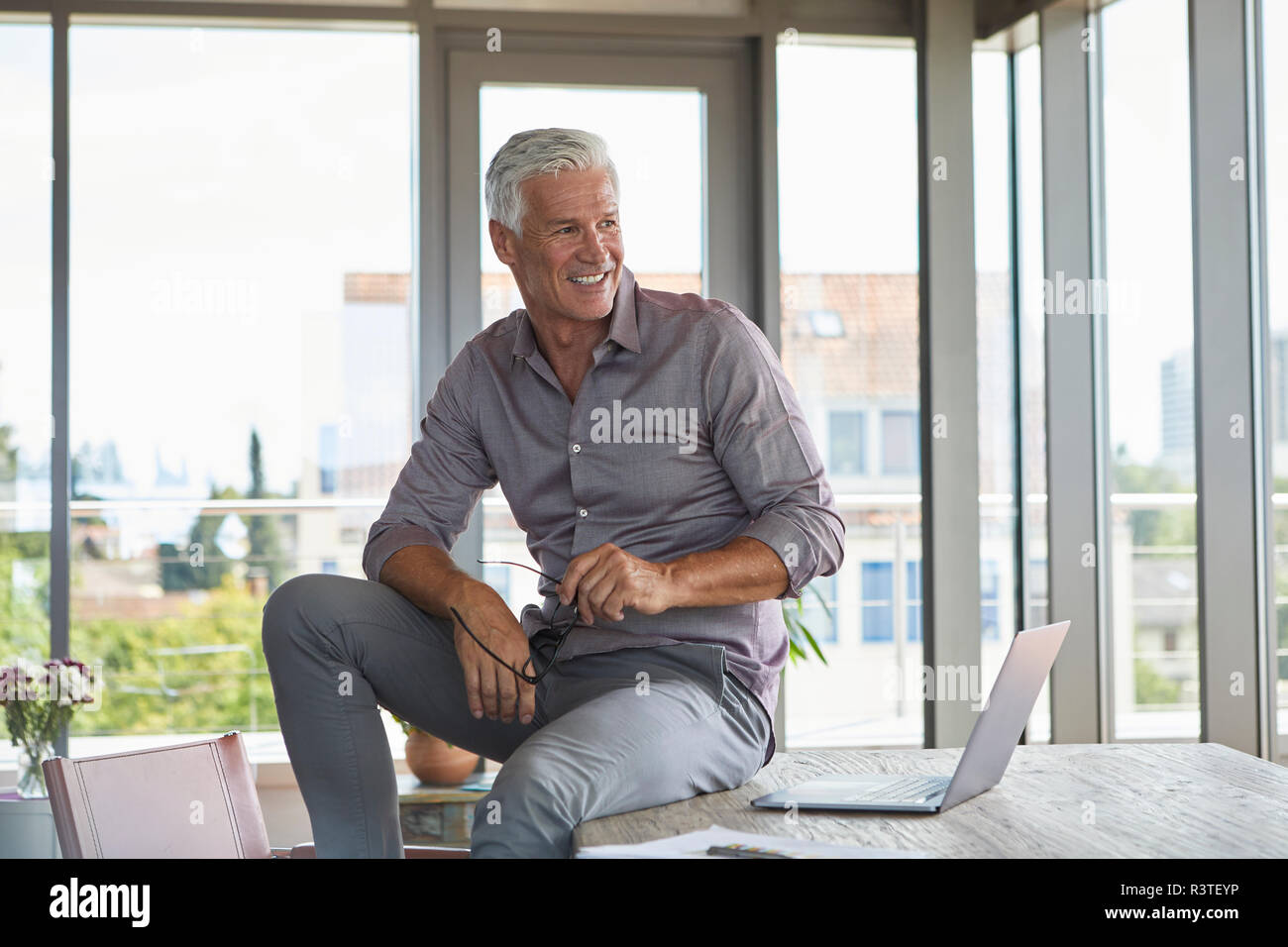 Lächelnd reifer Mann mit Laptop sitzen am Tisch zu Hause Stockfoto