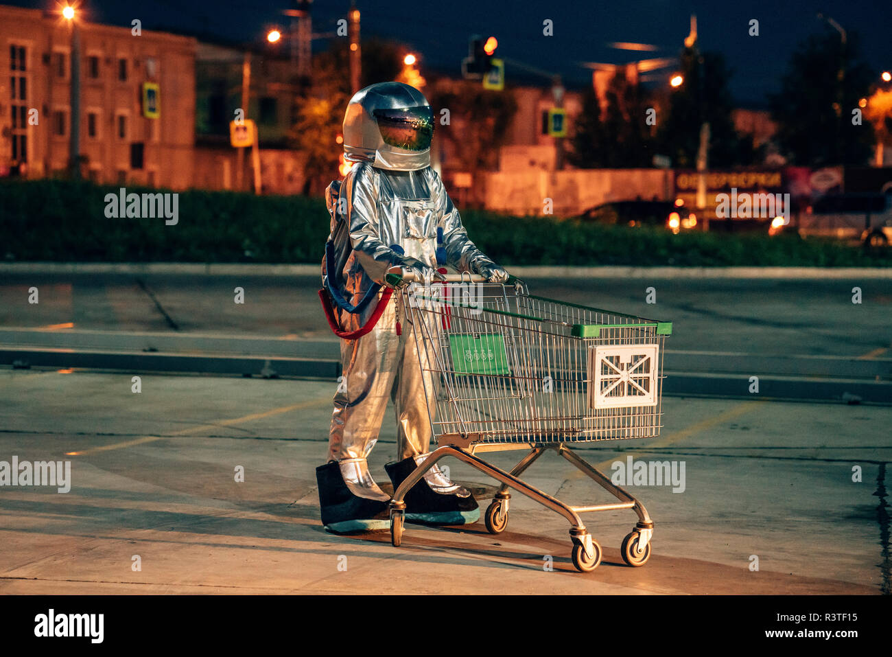 Spaceman in der Stadt in der Nacht auf Parkplatz mit Warenkorb Stockfoto